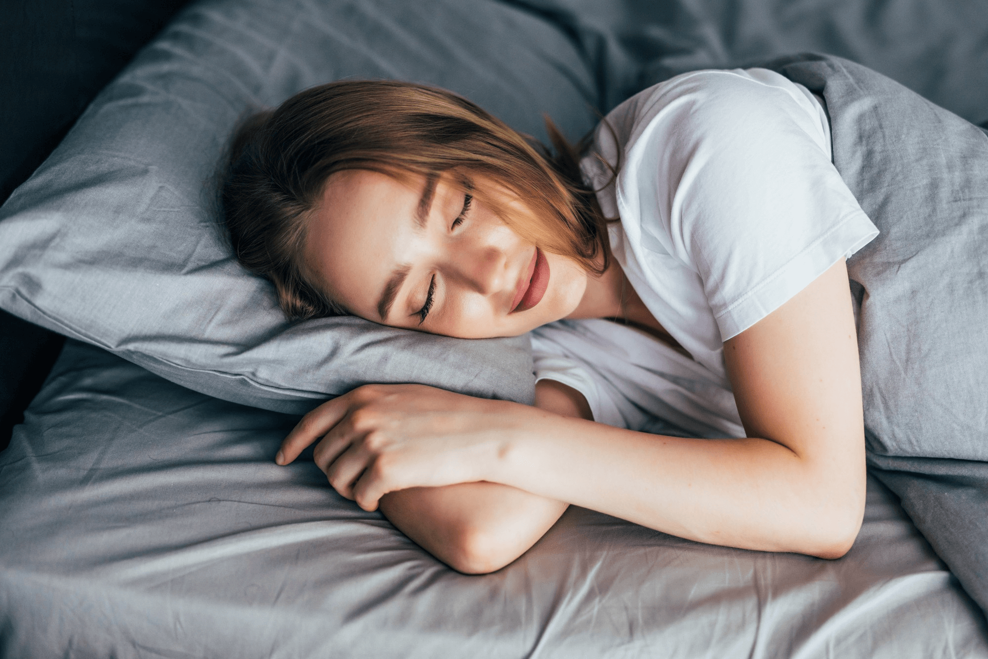 "Woman sleeping peacefully in warm bed prioritizing rest for winter weight loss."
